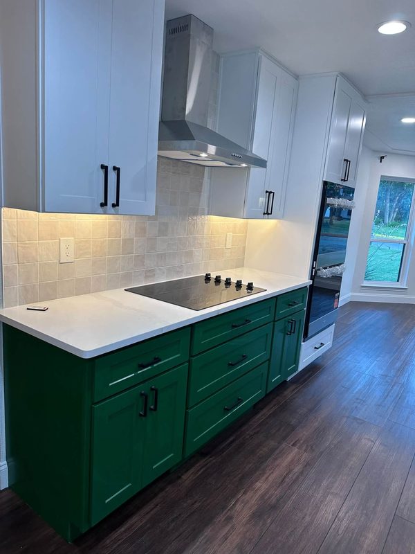 Green base cabinets, white uppers, cooktop and wall hood