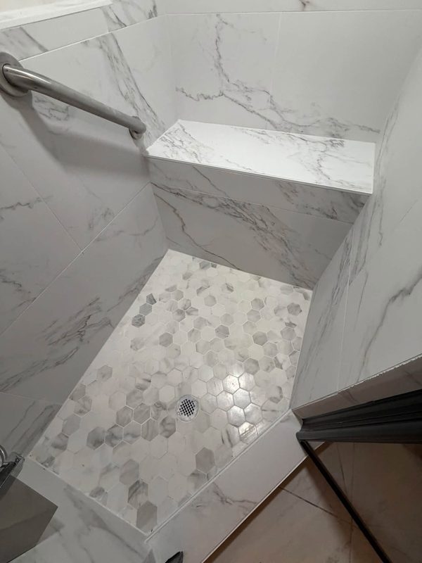 Tile bench and hex mosaic floor in a marble look shower