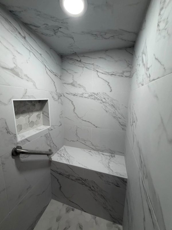 Marble look shower walls with a built in niche and bench